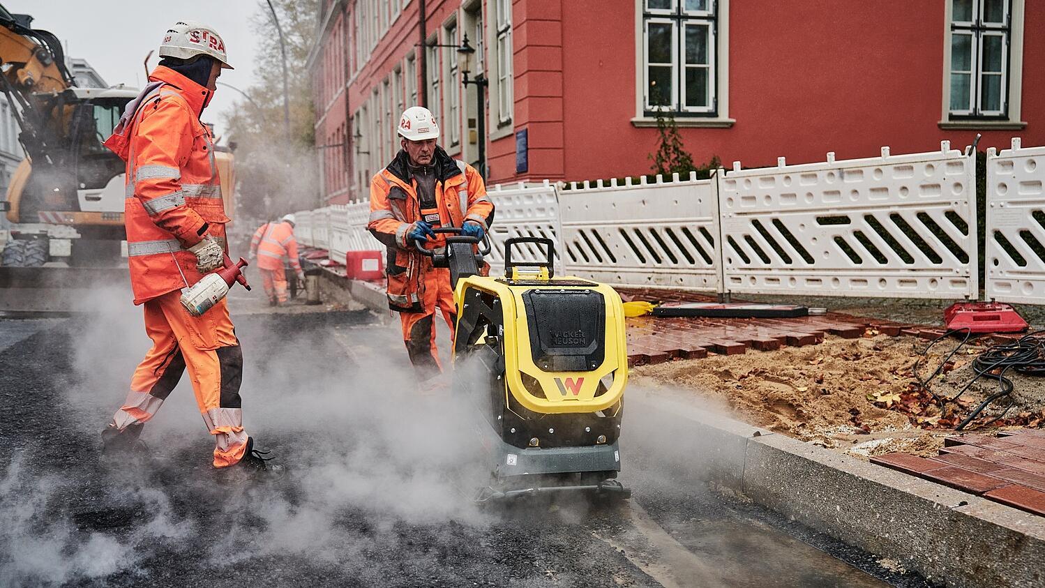 Pracownicy budowlani układający nawierzchnię drogi za pomocą maszyny DPU62