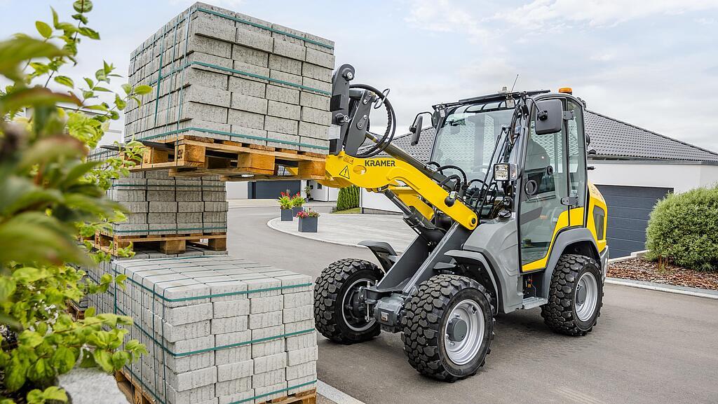 Ładowarka kołowa podnosi paletę z bloczkami betonowymi na utwardzonym terenie