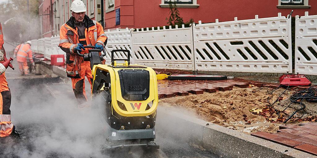 robotnik budowlany obsługujący płytę wibracyjną na placu budowy w centrum miasta