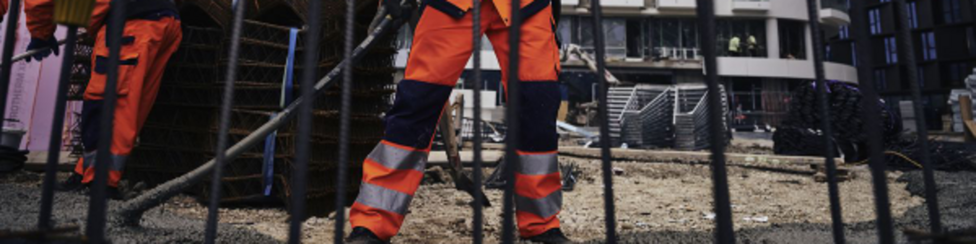 Robotnik budowlany na placu budowy, gdzie wibrator pogrążalny firmy Wacker Neuson zagęszcza beton.