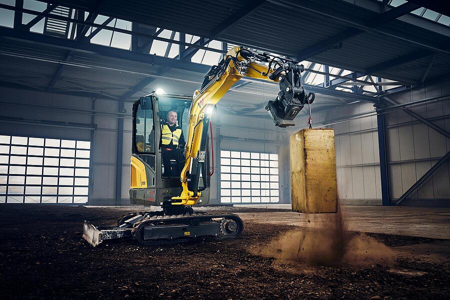 Wacker Neuson Minibagger ET25 hebt Betonblock in Halle mit hydraulischem Schnellwechsler