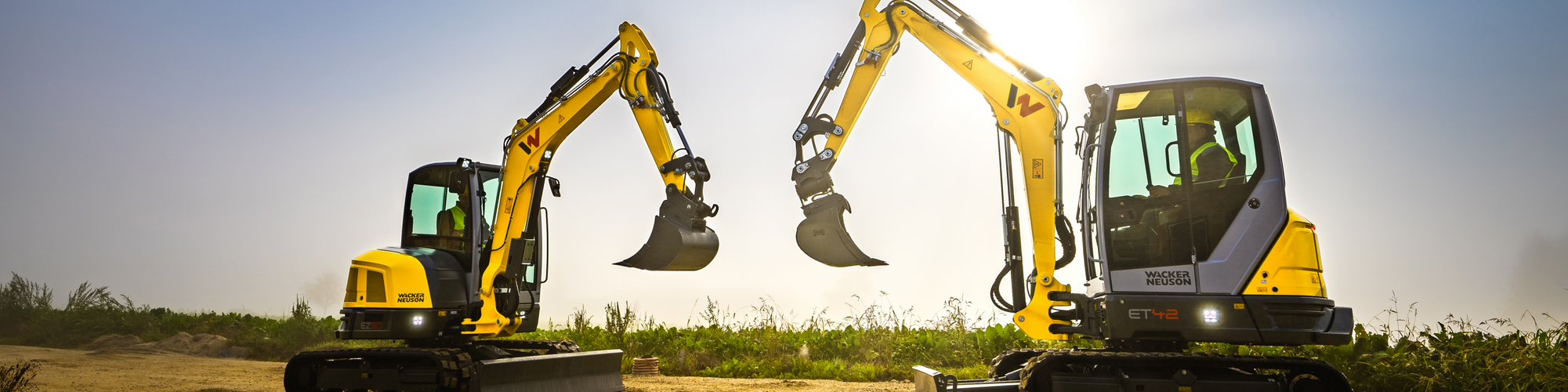 Two Wacker Neuson tracked excavators standing on a construction site.